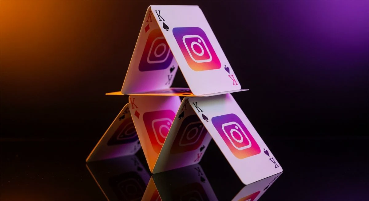 Casa de naipes con logos de Instagram sobre cristal oscuro