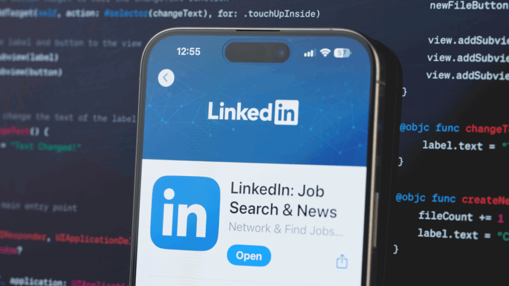 movil con linkedin en pantalla y codigo programatico de fondo