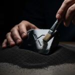 Arqueólogo limpiando un bloque de obsidiana con logo