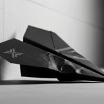 Avión de papel negro estrellado en suelo con logo minimalista