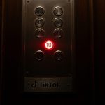 Botón rojo iluminado en panel de ascensor antiguo con logo TikTok