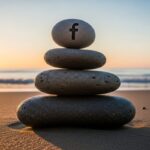 Cairn equilibrado con logo de Facebook en playa al amanecer