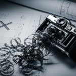 Cámara analógica con película fotográfica enredada sobre mesa
