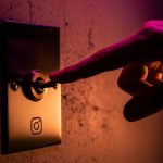 Mano apagando interruptor de palanca latón vintage en pared con logo de instagram