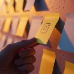 Mano coloca nota adhesiva amarilla con logo Instagram fondo borroso