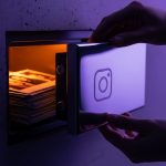 Manos abriendo caja fuerte futurista con logo de cámara Instagram grabado