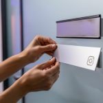 Manos instalando placa nueva con logo Instagram en puerta oficina moderna