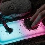 Manos limpiando artefacto brillante con logo TikTok en excavación arqueológica