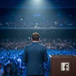 Persona en escenario con atril Facebook y audiencia difuminada