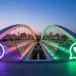 Puente moderno de cristal y acero con logotipo WhatsApp iluminado