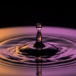 una única gota de agua en el momento exacto del impacto sobre una superficie de agua perfectamente quieta