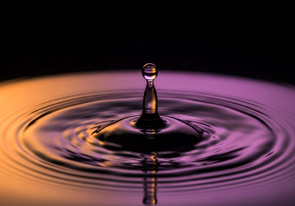 una única gota de agua en el momento exacto del impacto sobre una superficie de agua perfectamente quieta