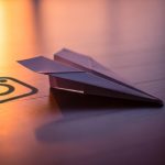 Avión de papel elegantemente doblado en suelo de madera oscura