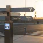 Cartel minimalista de metal con logo de LinkedIn iluminado al amanecer