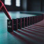 Dedo a punto de tumbar primer dominó con logo de TikTok