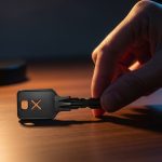 Mano coloca llave negra metálica con logo X sobre madera