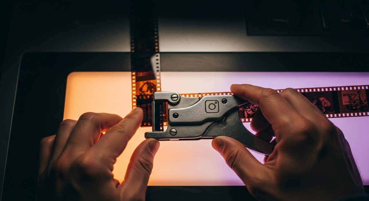 Manos de editor de cine usando herramienta vintage para splicing con logo de instagram