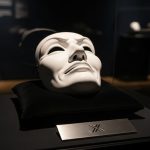 Máscara de teatro blanca con expresión sarcástica en vitrina