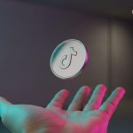 Moneda metálica pulida con logo de TikTok en mano abierta