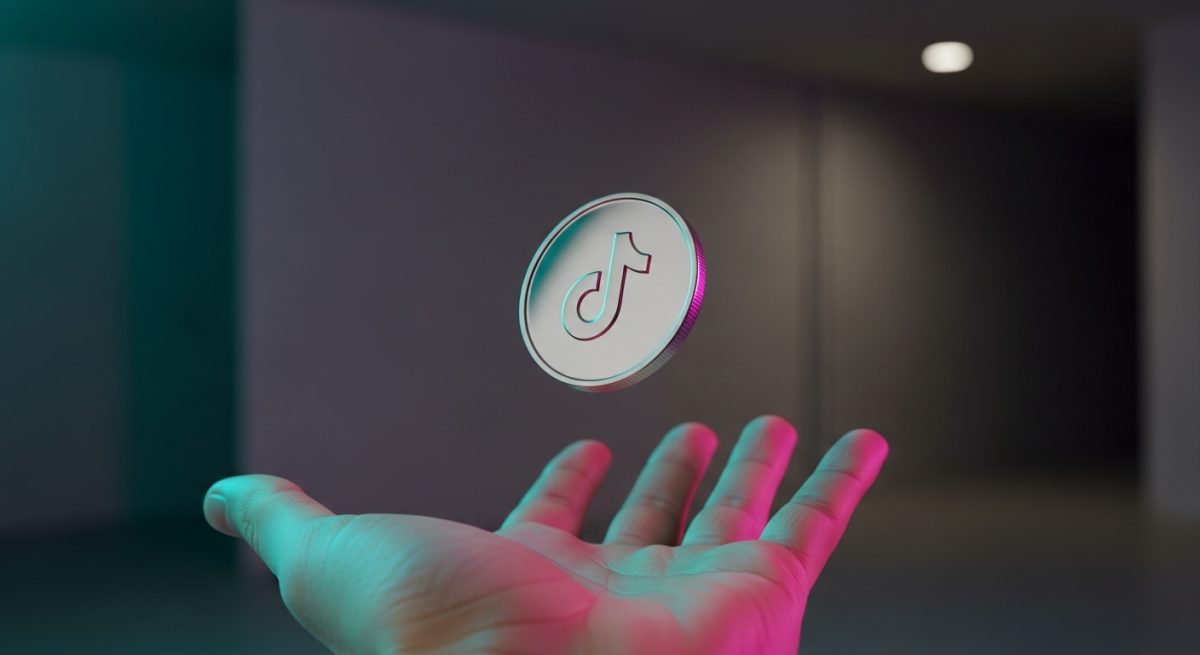 Moneda metálica pulida con logo de TikTok en mano abierta