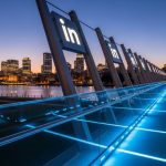 Puente peatonal moderno de acero y vidrio con logo de LinkedIn